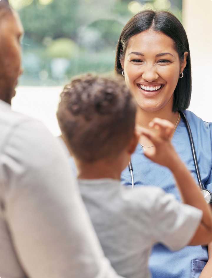 Doctor smiling at young patient in his father's arms.